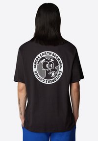 Camiseta de algodón negra con un gran gráfico circular blanco en la parte posterior que muestra un globo y una cara de dibujos animados, de manga corta y con un corte relajado.