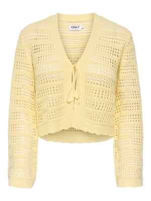 Cardigan court en maille ajourée jaune, manches longues, fermeture à nouer sur le devant, avec un bord festonné.