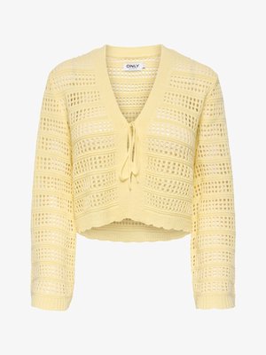Cardigan court en maille ajourée jaune, manches longues, fermeture à nouer sur le devant, avec un bord festonné.