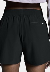 Svarta sportshorts med elastisk midja och en bakficka med dragkedja. Tillverkade av lätt tyg med en mjuk yta.