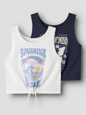 Dwa krótkie topy bez rękawów, jeden biały z nadrukiem "Sunshine Paradise" i falą plażową, drugi granatowy z motylem i wzorem kwiatowym, ułożone płasko.
