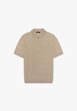 Bež kratka majica s pletenim pologrugom, kratkim rukavima i pola patent zatvaračem, prikazana ravno na bijeloj pozadini.