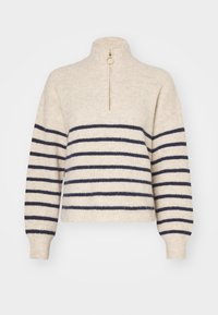 Jersey de punto crema con cuello alto, que presenta rayas horizontales en azul marino, una cremallera dorada y puños acanalados para añadir textura.