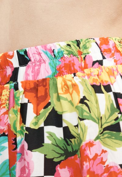 Ελαστική μέση σε ύφασμα με πολύχρωμο λουλουδάτο και ασπρόμαυρο καρό μοτίβο, παρουσιάζοντας κοντινό πλάνο λεπτομέρειας ρούχου.