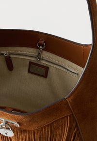 Pruun seemisnahast käekott tekstureeritud pinnaga, millel on helepruun nahast sisemus, tõmblukuga tasku ja metallist kinnitus.