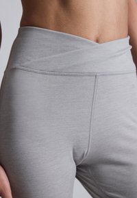Gray high-waisted leggings feature a smooth, soft texture with flatlock seams and an elastic waistband, designed for comfort and flexibility.