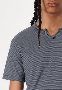 Tummansininen ja valkoinen raidallinen lyhythihainen paita Henley-puolelle, jossa on kaksi nappia ja pehmeä rakenne. Lähikuva, joka näyttää ylävartalon.