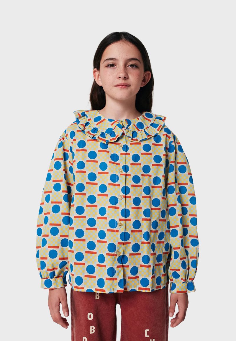 Camicia button-up realizzata in tessuto leggero, con una base gialla decorata da cerchi blu, motivi a griglia e un colletto arricciato.