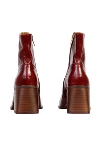 Botas de tobillo de cuero rojo con un acabado brillante, que presentan una puntera cuadrada y un tacón de bloque de madera de altura media. Cierre de cremallera lateral.