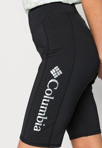 Černé sportovní šortky s vysokým pasem, vybavené stříbrným logem Columbia a prošíváním podél stran. Hladký, pružný materiál.