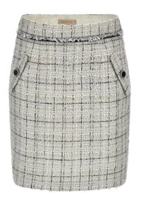 Jupe mini en tweed noir et blanc avec une surface texturée, dotée de poches latérales et d'un ourlet effiloché, estampillée d'une étiquette "GUESS".