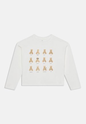 Chemise blanche à manches longues avec un imprimé sur le devant représentant 12 ours en peluche disposés en trois rangées, chacun associé à un trait de personnalité.