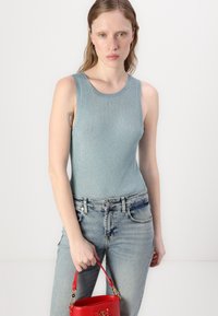 Hele sinine ribaga tank top ümmarguse kaelusega, mis on kombineeritud kulunud heledate teksadega. Käes on väike punane käekott koos kuldse aktsendiga.