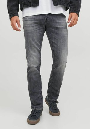 Mörkgrå jeans med en urtvättad textur och rak benstil, parat med marinblå sneakers. Diskreta sömdetaljer och femficksdesign.