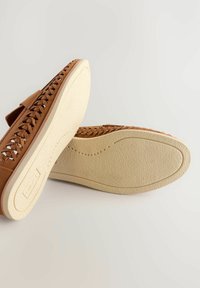 Braune gewebte Schuhe mit glatter Oberfläche, leichten Gummisohlen und minimalistischer Gestaltung. Mit einem Klettverschluss für eine verstellbare Passform.