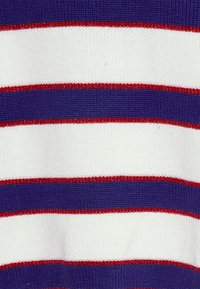 Knitted sweater featuring horizontal stripes in dark purple, white, and narrow red accents. Textured fabric with a ribbed pattern.