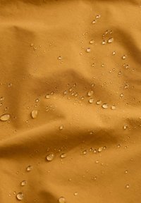 Waterafstotende stof in een warme mosterdgele kleur, voorzien van meerdere druppels op een gladde, gestructureerde oppervlakte. Gekreukte uitstraling.