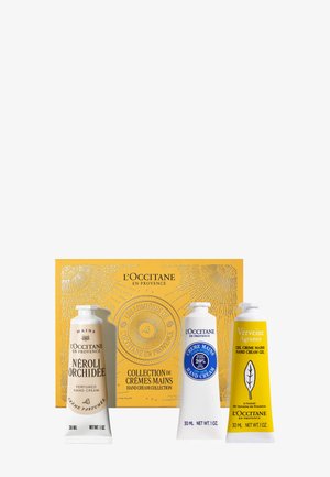 Collezione di creme per le mani L'Occitane con tre tubetti: bianco con accenti blu, giallo con motivo a foglie e una confezione dorata.