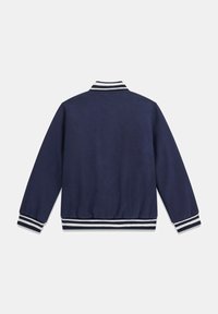 Giacca blu navy con colletto e polsini a coste caratterizzati da strisce bianche. Texture liscia, vestibilità regolare e vita elastica.