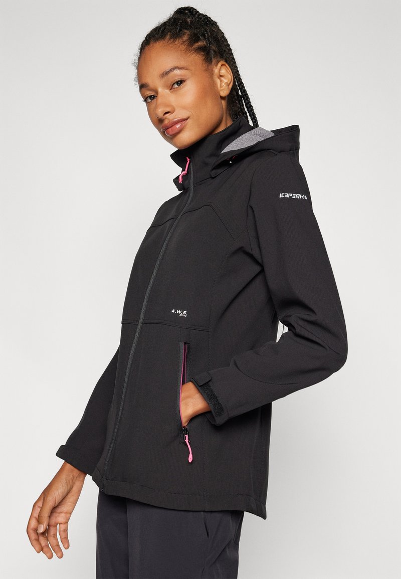 Schwarze Softshelljacke mit Kapuze, ausgestattet mit einem Frontreißverschluss, pinken Akzenten und zwei mit Reißverschluss versehenen Taschen. Auffälliges Logo auf der Schulter.