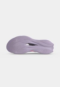 Semelle d'une chaussure de sport violette avec une bande de roulement texturée et une découpe visible au niveau de la voûte plantaire affichant le mot "PWRPLATE."