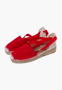 Espadrilles de lona roja con suela de yute trenzado, que cuentan con lazos de tela entrecruzados y un diseño de parte trasera abierta. Tejido texturizado y detalles cosidos.
