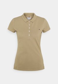 Polo beige manches courtes avec cinq boutons et petit logo sur la poitrine gauche, présenté sur fond blanc uni.