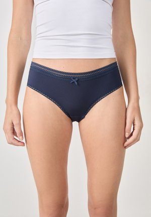 Bañador de bikini para mujer en azul marino, con textura acanalada, borde de encaje y un lazo de satén central en la cintura. Corte clásico de hipster.