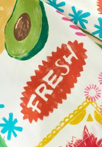 Kankaita, joissa on värikkäitä kuvioita, mukaan lukien avokadon puolikas, punainen "FRESH"-etiketti ja kirkkaat kukat valkoisella taustalla.