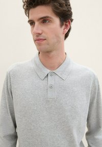 Grijze lange mouw polo shirt, gemaakt van een textuurstof, met een geribbelde kraag en een knoopsluiting met drie bijpassende knopen.