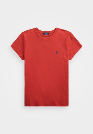 Czerwona koszulka z krótkim rękawem i okrągłym dekoltem z małym niebieskim logo Polo Ralph Lauren na lewej piersi na białym tle.
