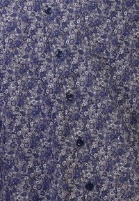 Knapp-up skjorta i mörkblått med blommönster; har små knappar och ett mjukt, texturerat tyg.