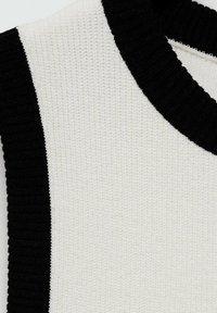 Knit sweater featuring a textured white body with black ribbed neckline and side accents, showcasing a modern, contrasting color design.