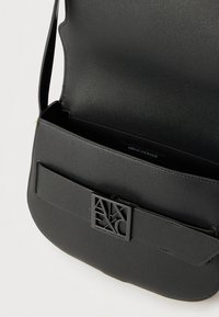 Μαύρη δερμάτινη τσάντα ώμου με ανοιχτό καπάκι, με μεταλλική αγκράφα λογότυπου Armani Exchange στην μπροστινή τσέπη.