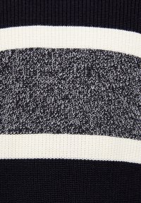 Pull en tricot avec des rayures horizontales noires et blanches ; le tissu texturé présente une section noire unie et un motif de maille épaisse.