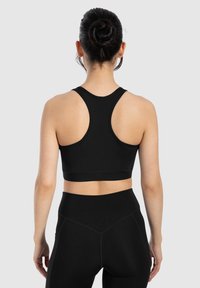 Top corto atlético negro con diseño de espalda nadadora, hecho de una tela suave y elástica. Presenta una silueta ajustada y bandas anchas.