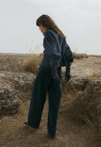 Navy textured sweater and wide-leg pants, paired with black leather gloves. The outfit features oversized sleeves and a relaxed fit.