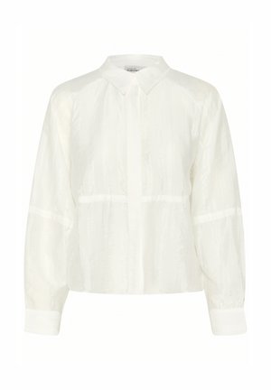 Blouse blanche à manches longues avec un col à boutons, présentant un tissu texturé et un design cropped, complétée par des manches à poignets.