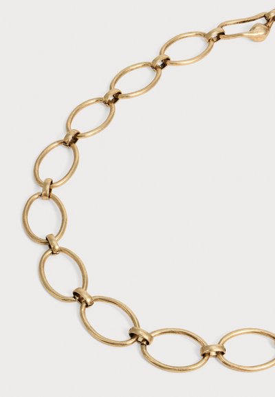 Collier chaîne en or avec de grands maillons ovales reliés par de petits anneaux sur un fond clair uni.