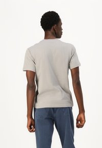 Grå bomulds t-shirt med rund halsudskæring og korte ærmer, der har en glat tekstur og en afslappet pasform, set fra ryggen.