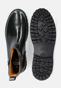 Stivali ankle in pelle verde scuro con finitura lucida, dotati di zip e suola in gomma nera testurizzata con grip a motivo.