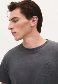 Grijze katoenen t-shirt met een ronde hals, voorzien van een subtiele logoprint op de linkerborst en een zachte, gestructureerde afwerking.