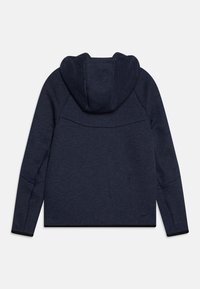 Námornícky mikina s jemnou textúrou, obsahujúca kapucňu so šnúrkami a plochými švami. Má logo na dolnej ľavej strane chrbta a manžety v kontrastnej čiernej farbe.