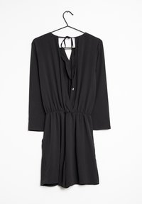 Svart långärmad jumpsuit med V-ringning och knytning bak. Har midjeresår och avslappnad passform på shortsen. Slät textur.