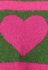 Ein pinkfarbens Herzmuster, das in einen grün-rosa gestreiften Stoffhintergrund eingestrickt ist.
