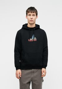 Crna dukserica s prednjim džepom, koja ima šareni grafički dizajn jedrenjaka i planina. Mekana tekstura, podesive špice na kapuljači.