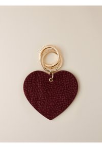 Porte-clés en cuir texturé rouge foncé en forme de cœur avec deux anneaux dorés entrelacés sur un fond neutre.