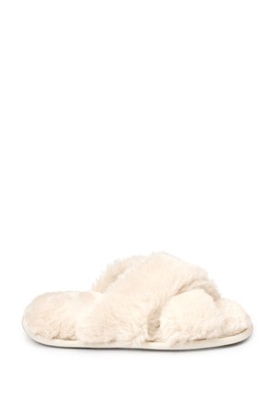 Chausson ouvert d'un blanc crème doux et duveteux avec des brides croisées et une semelle plate, vu de côté sur un fond blanc.