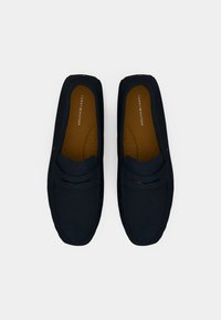 Mørkeblå loafers lavet af blødt materiale med rund tå, kontrastfarvet brun indersål og dekorative syninger.