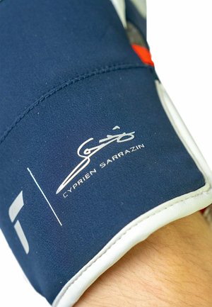 Marineblaue Sporthandschuhe mit weißen Akzenten, strukturiertem Stoff und dem Schriftzug "Cyprien Sarrazin" in Weiß auf dem Handgelenk.